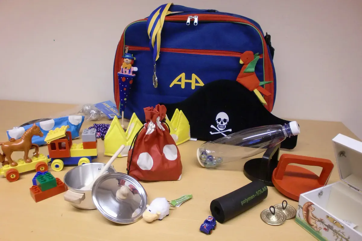 The Kids-AHA test kit: a blue bag with the AHA logo, surrounded by the toys it contains.